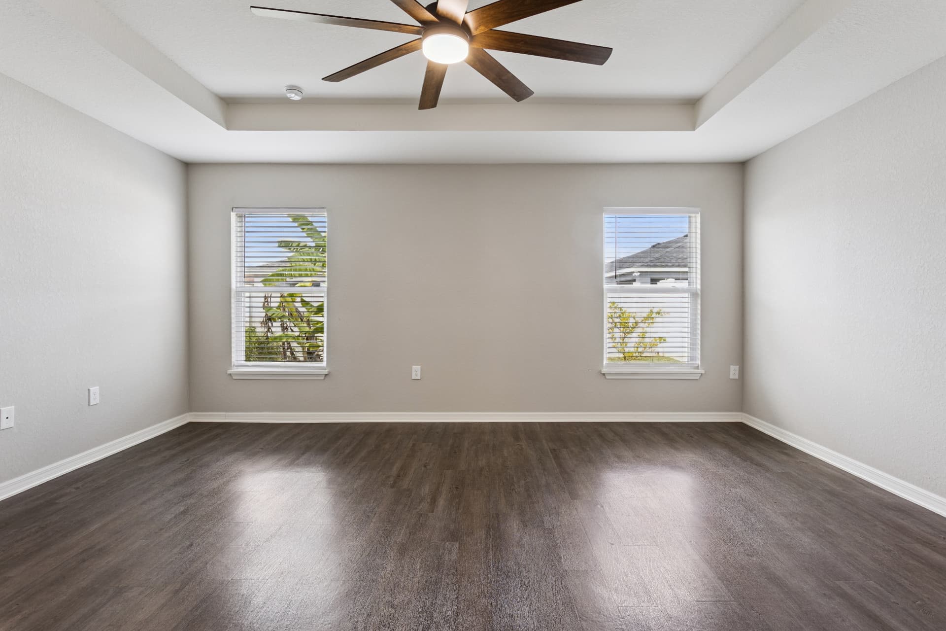Primary bedroom with ceiling fan and two windows